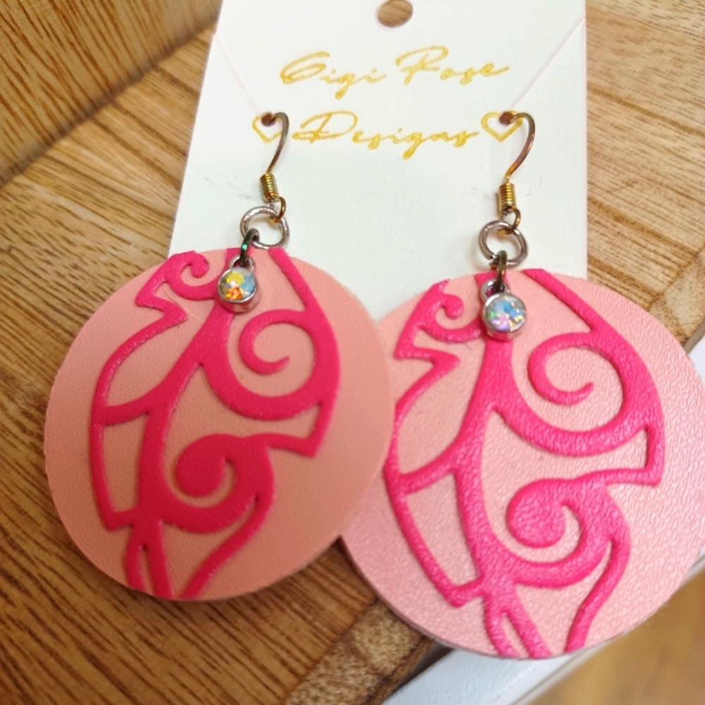 Pink round faux leather earrings with leaf and gem detail.